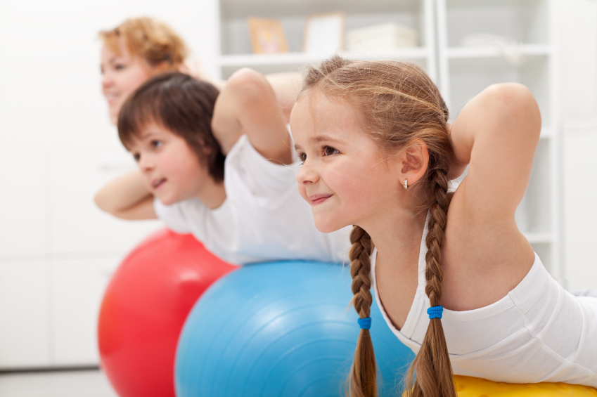 Kids and woman doing exercises with balls